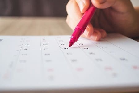 Hand with a pen writing on calendar. Credit: https://www.istockphoto.com/au/portfolio/kwangmoozaa