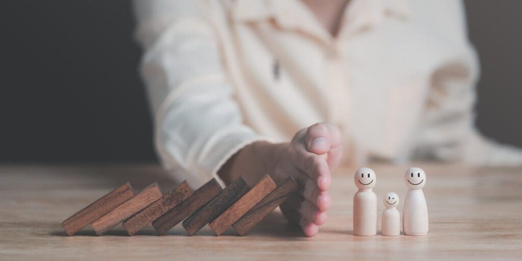 Human hand blocking dominos from falling onto little figurines. Source: https://www.istockphoto.com/portfolio/chaylek