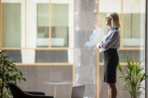 Businesswoman looking outside office window, pondering. Credit: https://www.istockphoto.com/portfolio/fizkes