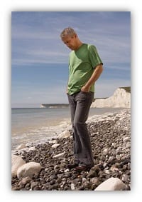 man walking over pebbles on a beach